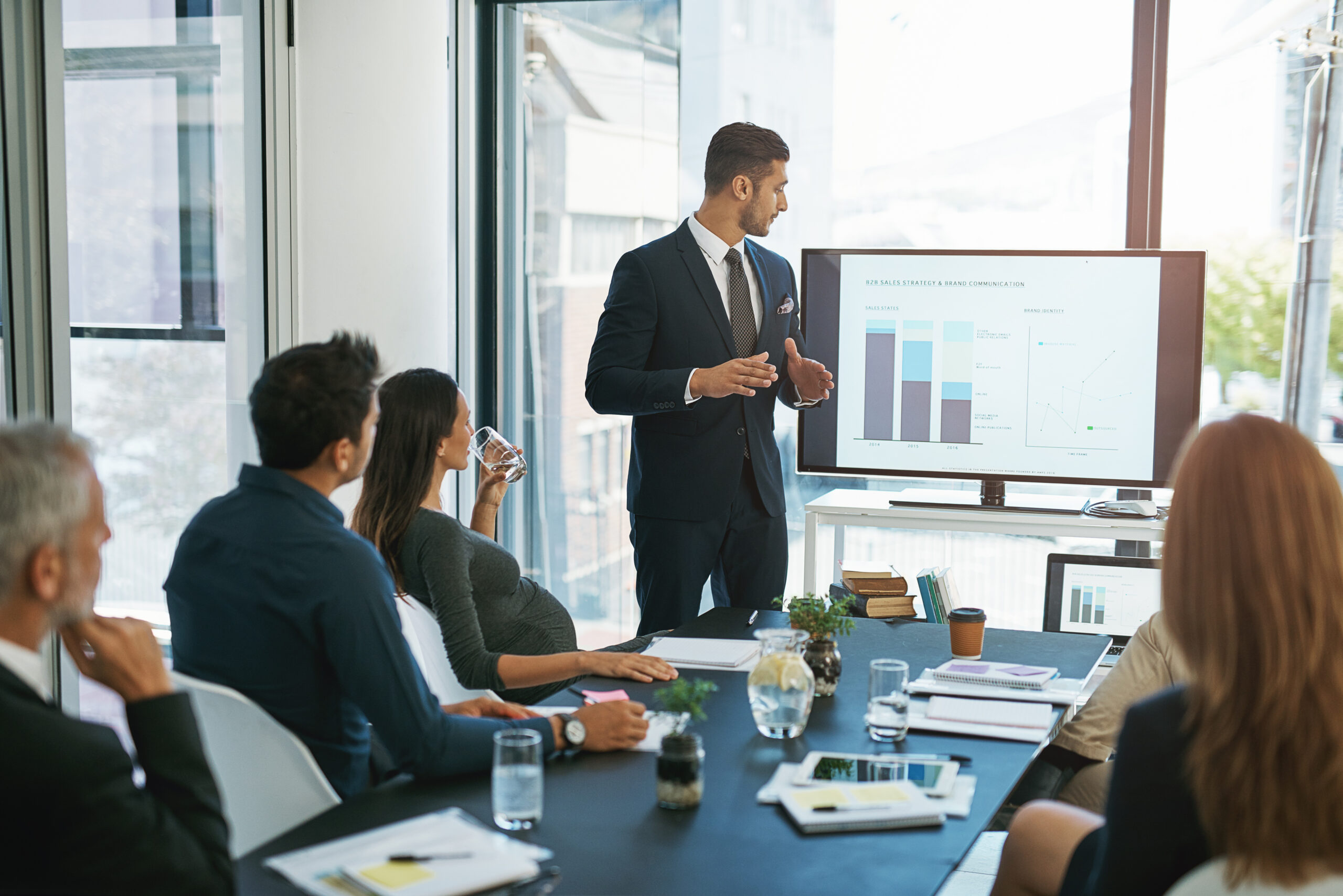 A business professional presenting data on a screen during a boardroom meeting