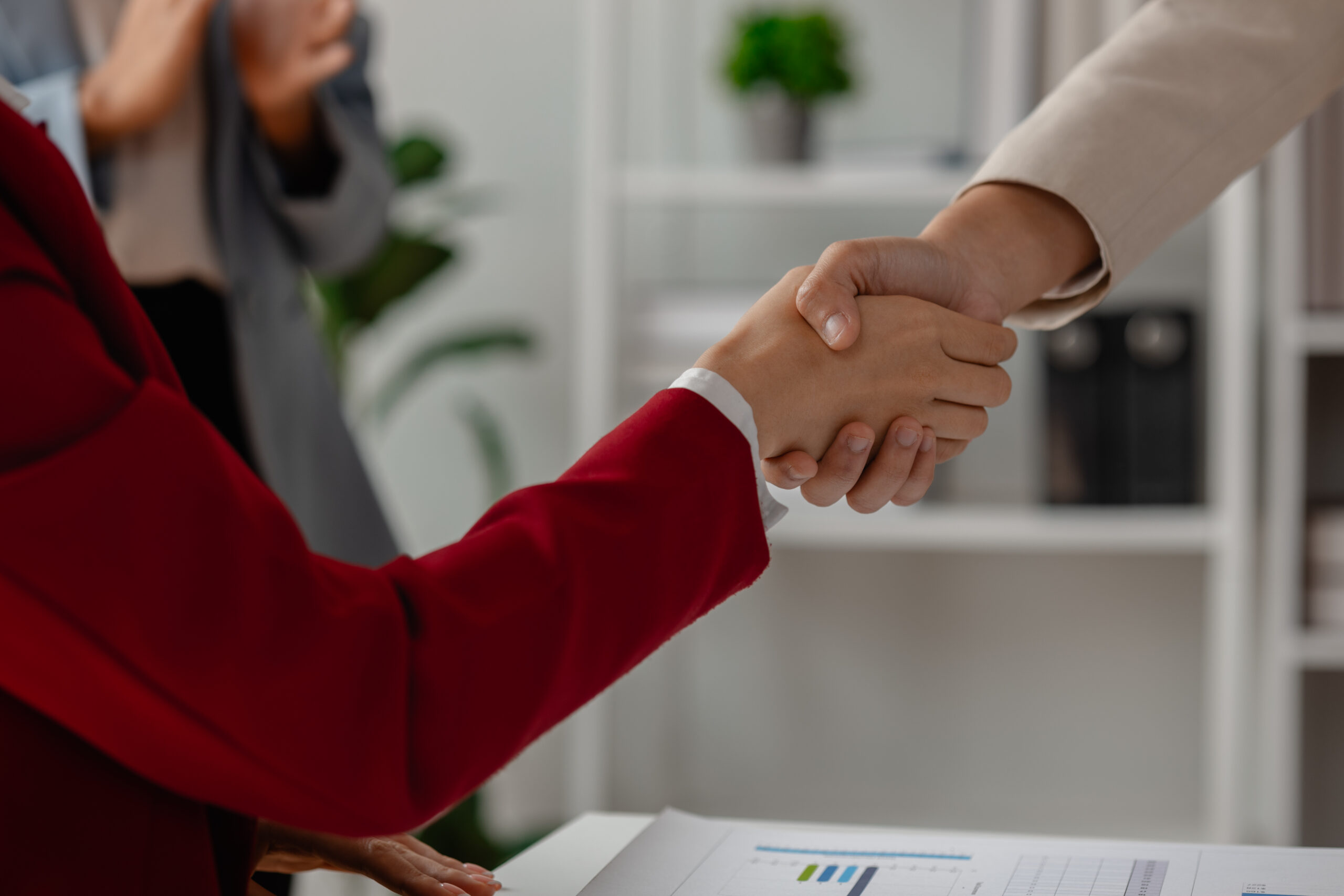 Two business professionals shaking hands in a cozy office setting.
