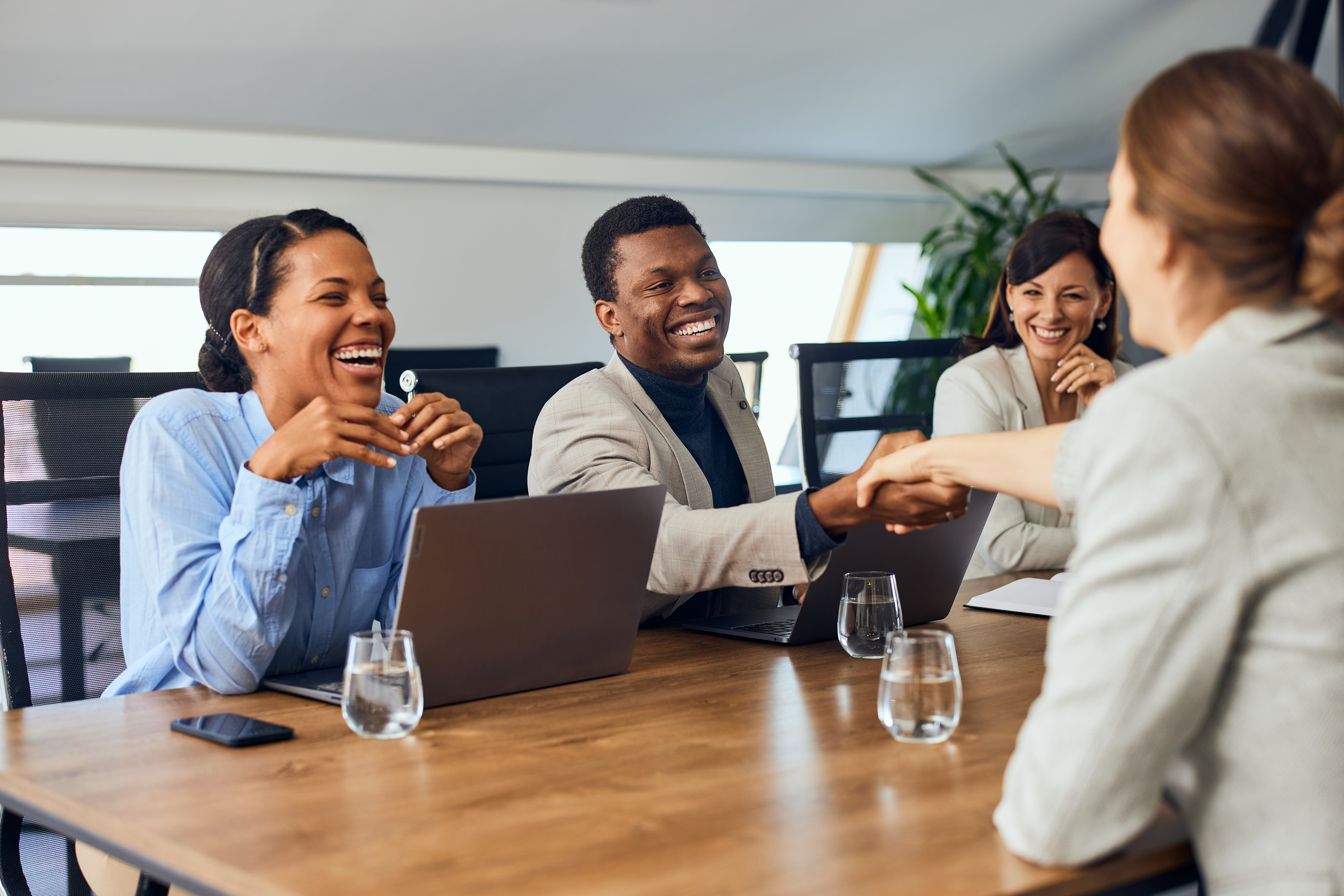 A business professional happily shaking hands with a client during a meeting.