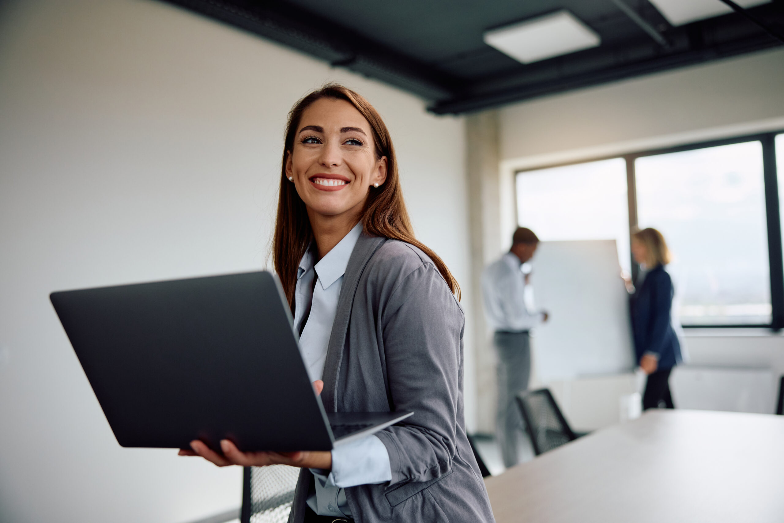 A young business professional holding a laptop.