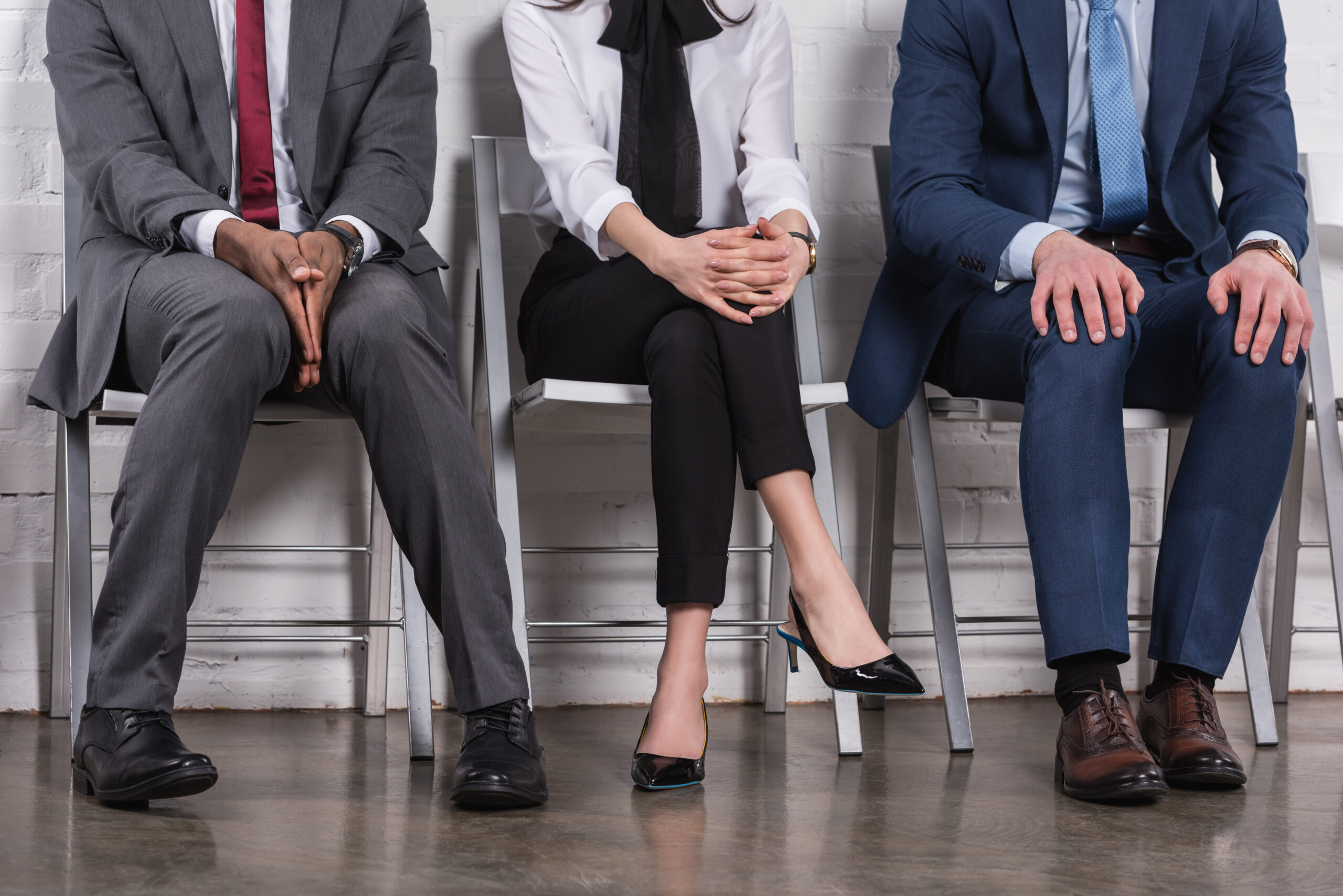Three job applicants sitting in a row in a modern corporate environment