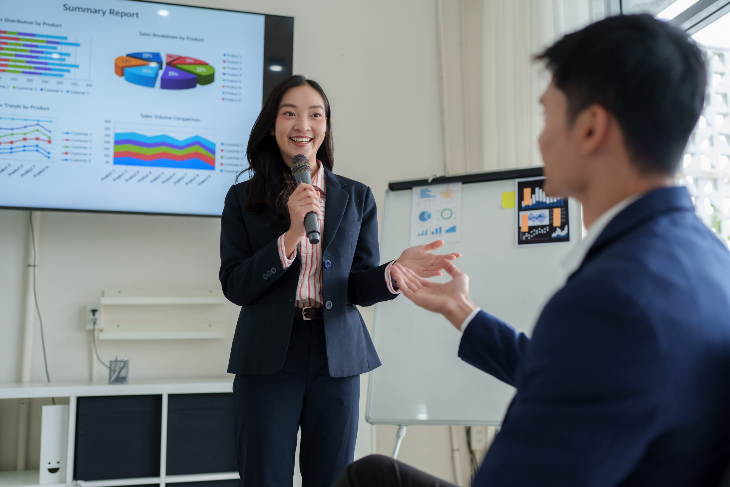 A standing young professional presenting data on a big screen